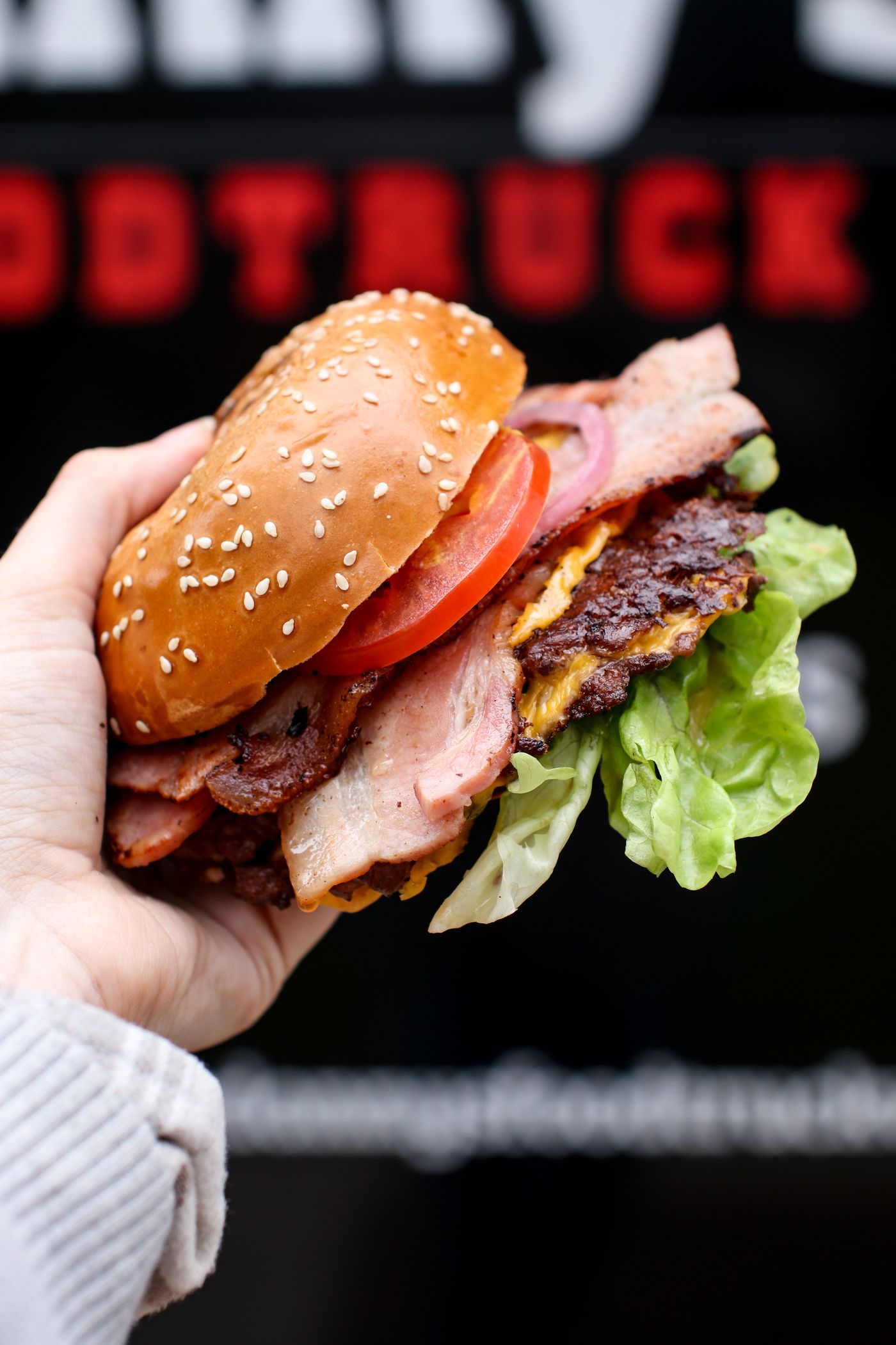 Danny's Bacon & Cheese Deluxe smash burger held up close